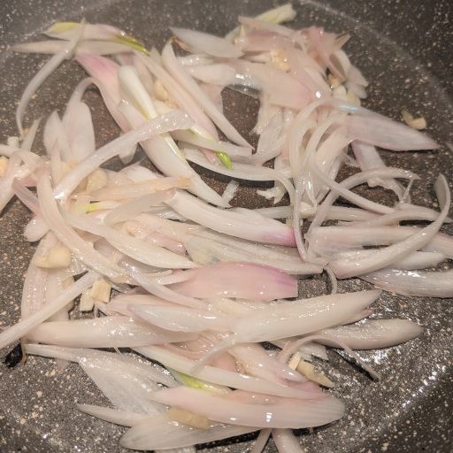 Sliced onion and garlic softening in olive oil at the start of kapunata